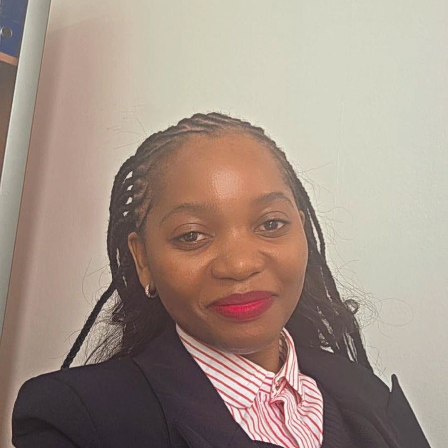 Dr. Gloria Manyeruke, smiling, wearing a dark blazer over a striped shirt